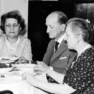Here's a brief summary of the image: Four people seated at a table, having a meal.