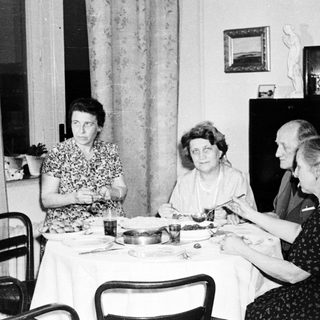 Here's a brief summary of the image: Four people seated at a table, seemingly having a meal.