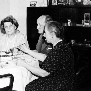 Here's a brief summary of the image: Four people seated at a table, seemingly having a meal.
