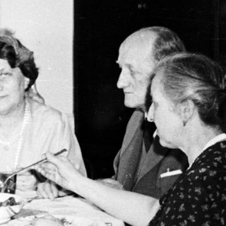 Here's a brief summary of the image: Four people seated at a table, seemingly having a meal.