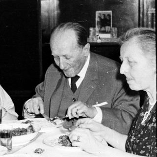 Family members seated at a table, eating a meal.