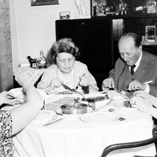 Family members seated at a table, eating a meal.