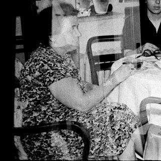Here's a brief summary of the image: Family gathers around a table for a meal.