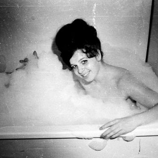 Woman in a bathtub, surrounded by bubbles.