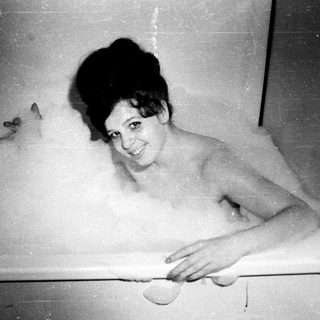 Woman in a bathtub, surrounded by bubbles.