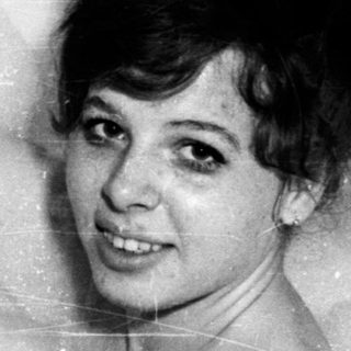 Woman in a bathtub full of bubbles, smiling.