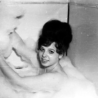 Woman in a bathtub full of bubbles, smiling.