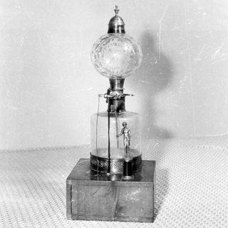 Vintage mechanical man figure displayed within a glass dome.