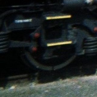 Red electric locomotive sits on tracks under a cloudy sky.