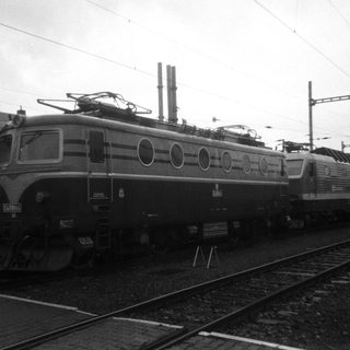 Green and blue electric locomotive standing on train tracks.