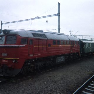 Red locomotive and train cars sit on a track.