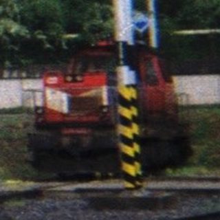 Vintage steam locomotive sits on tracks near a building.