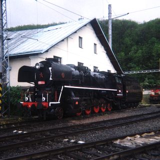 Vintage steam locomotive sits on tracks near a building.