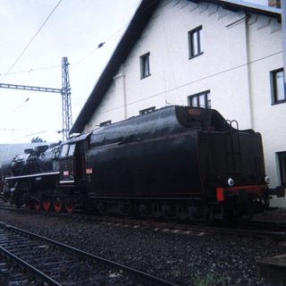 Black steam locomotive sits on tracks near a building.