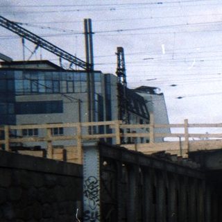 Roadway passes under a bridge with graffiti and foliage.