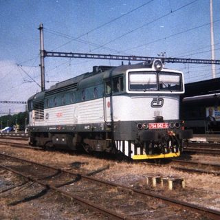 Locomotive on train tracks, station platform in the background.