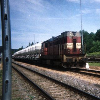Train engine and cars on tracks near wooded area.
