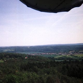 Aerial view of forested landscape and a distant village.