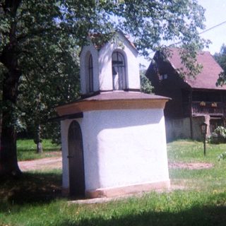 A small, ornate structure sits in a grassy area.