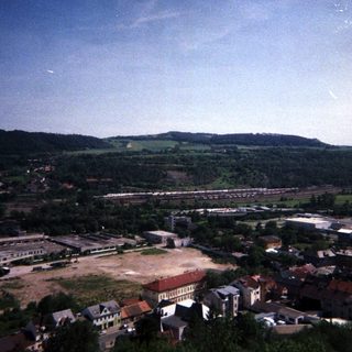 Aerial view of a town with industrial area and forested hills.