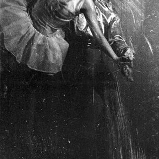 Here's a brief summary of the image: Ballerina in mid-air, captured in a dramatic, grayscale pose.
