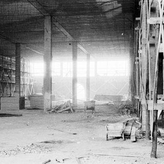 Construction site interior, scaffolding and lumber visible.