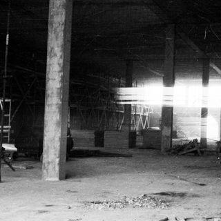 Black and white image of a dusty, empty warehouse interior.