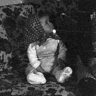 Elderly woman sits with a child on a floral sofa.