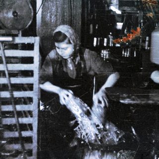 Here's a brief summary of the image: Woman working in a dark, industrial setting, possibly fishing.