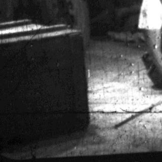 Worker sits on floor in a cluttered, industrial-like space.