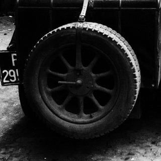 Vintage car's rear tire and license plate in black and white.