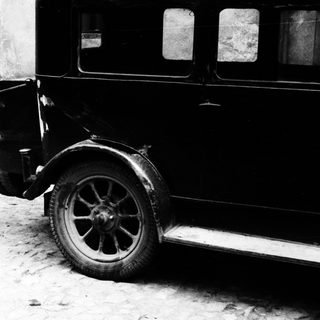 Vintage car parked beside a door and wall.