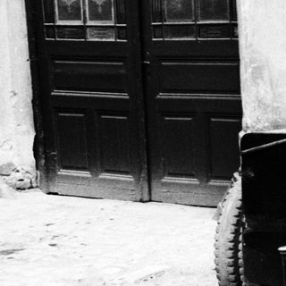 Vintage car parked beside a door and wall.
