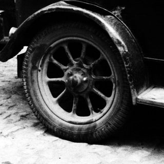 Vintage car parked beside a door and wall.