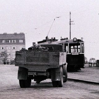 Black and white image of a street with construction and tram.