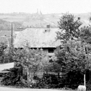 Black and white photo of a town with trees and a barrier.