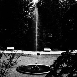 Fountain shoots water in a garden setting.