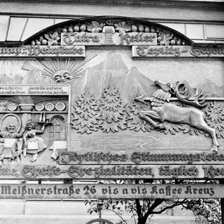 Wood carving depicts a wine cellar scene with a stag.