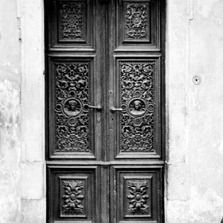 Detailed, ornate wooden door set into a stone wall.