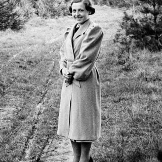 Woman stands on a path in a wooded area.