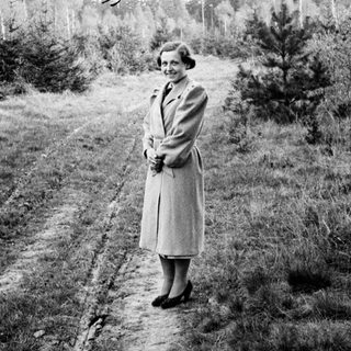 Woman stands on a path in a wooded area.