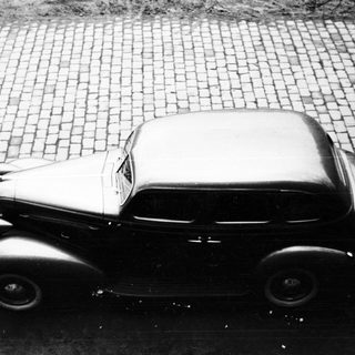 Vintage car parked on a cobblestone street.