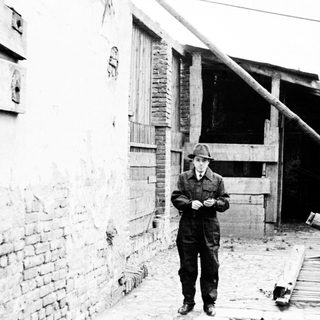 Man stands near a building with a fallen beam.