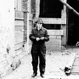 Man stands near a building with a fallen beam.