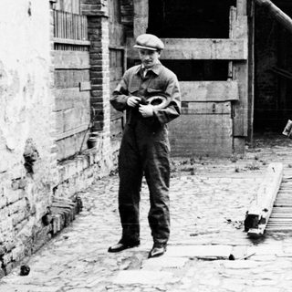 Man stands in a dilapidated yard with fallen lumber.
