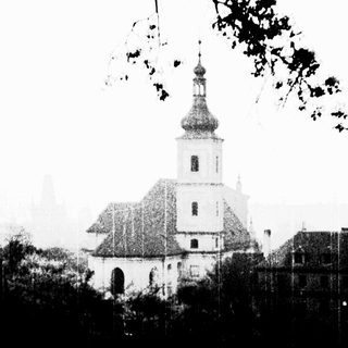 Church with a tower framed by tree branches.