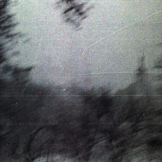 Blurred image of a dark, textured surface with visible streaks.