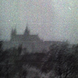 A grainy, monochrome image of a dark, silhouetted landscape.
