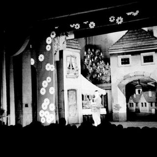 Man stands before a whimsical, detailed, architectural stage set.
