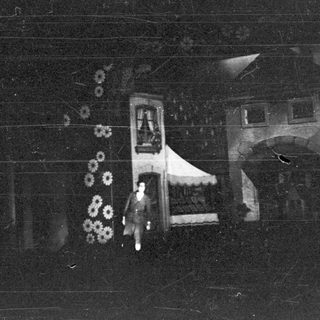 Here's a brief summary of the image: Person stands near a building with an arched doorway.